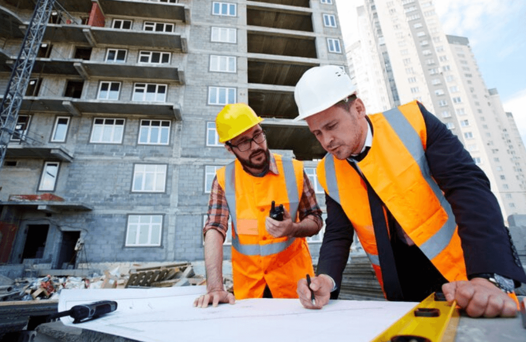 a construction contractor discussing project plans with a client on a construction site, highlighting the importance of contractors insurance in Columbus, Ohio.